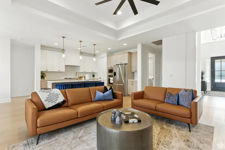 Living area featuring recessed lighting, light wood finished floors, ceiling fan, and a raised ceiling