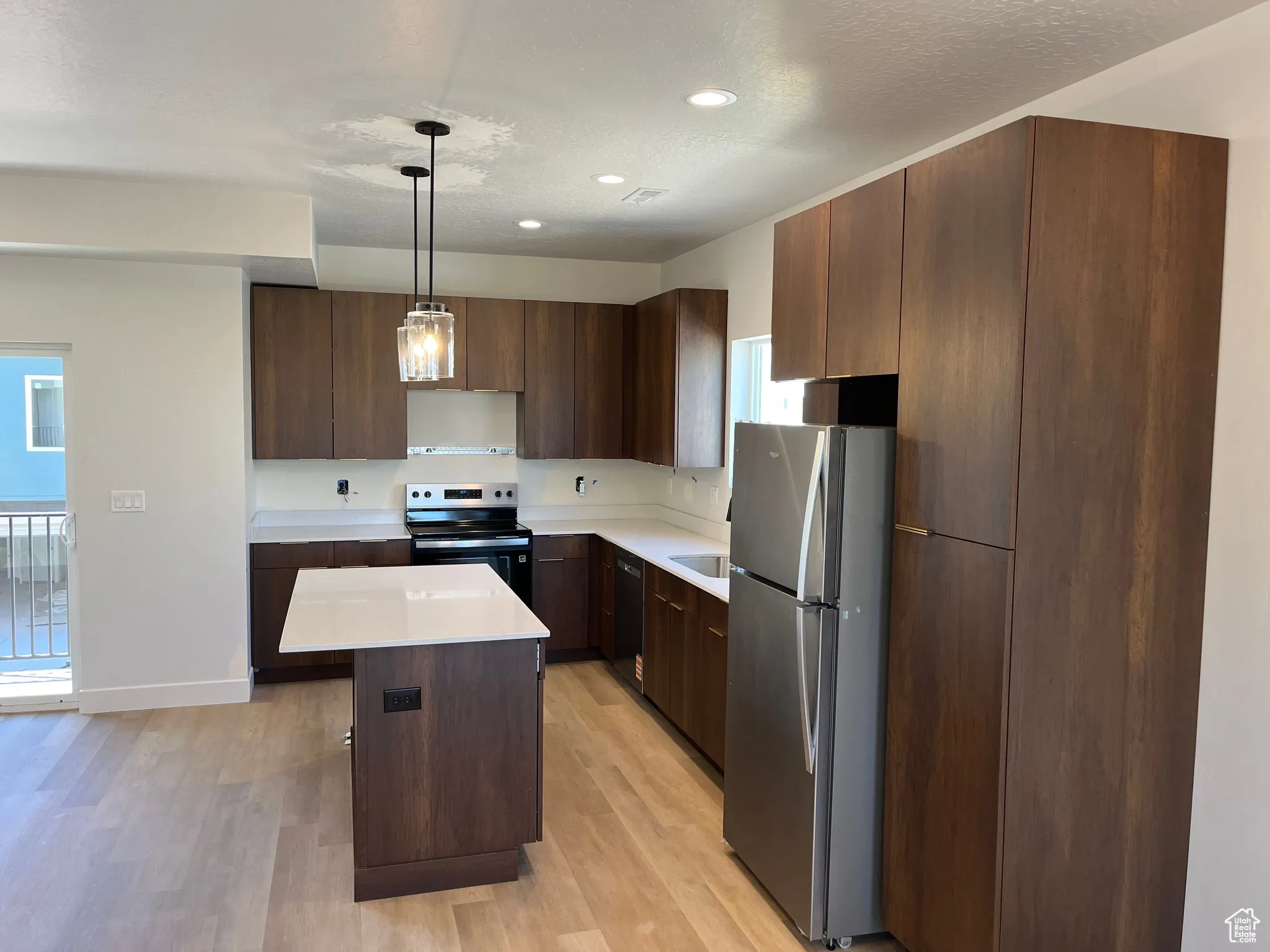 Kitchen featuring stainless steel appliances, light wood-type flooring, light countertops, a kitchen island, and recessed lighting