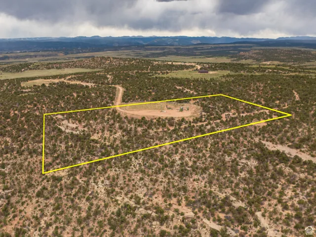 Aerial view of sparsely populated area with property parcel outlined and mountains
