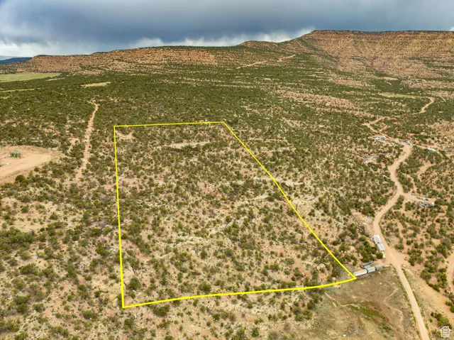 Aerial view of sparsely populated area with property parcel outlined and a mountain backdrop