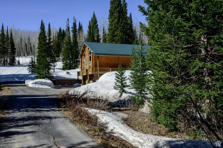 Snow covered property with a metal roof and a view of trees