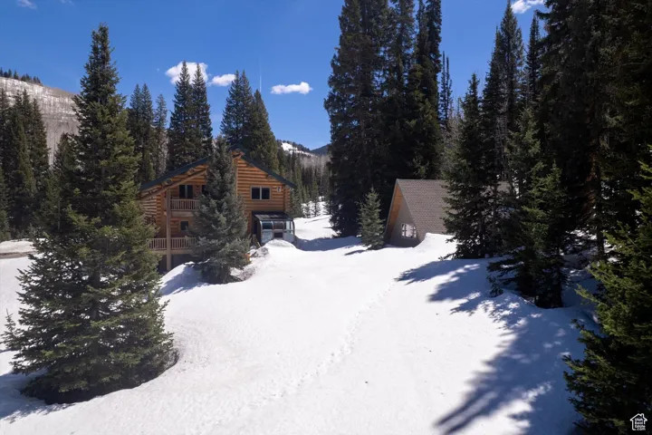 Snow covered property with log veneer siding