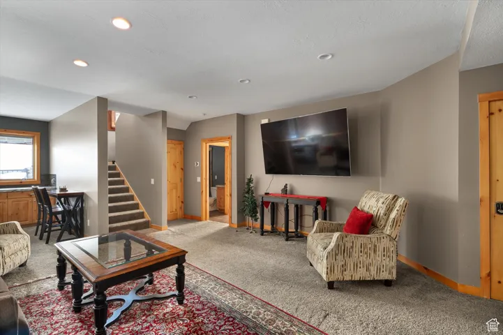 Living room featuring carpet, recessed lighting, and stairs