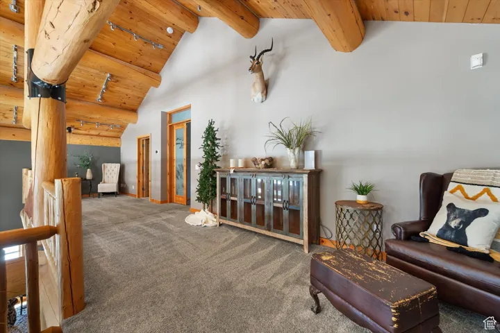 Living area featuring a wood ceiling with exposed beams, carpet flooring, and high vaulted ceiling