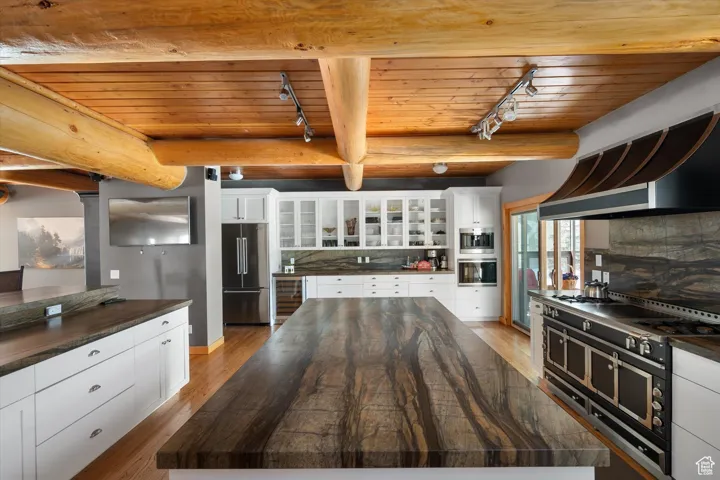 Kitchen with track lighting, wood ceiling, wood finished floors, appliances with stainless steel finishes, and a kitchen island