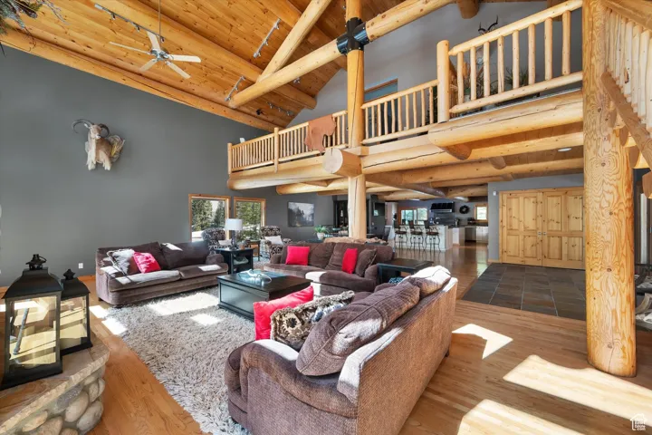 Living room with a ceiling fan, high vaulted ceiling, a wood ceiling with exposed beams, and wood finished floors