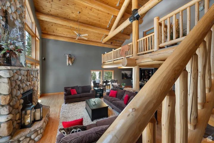 Living area with high vaulted ceiling, a wooden ceiling with exposed beams, a ceiling fan, and wood finished floors