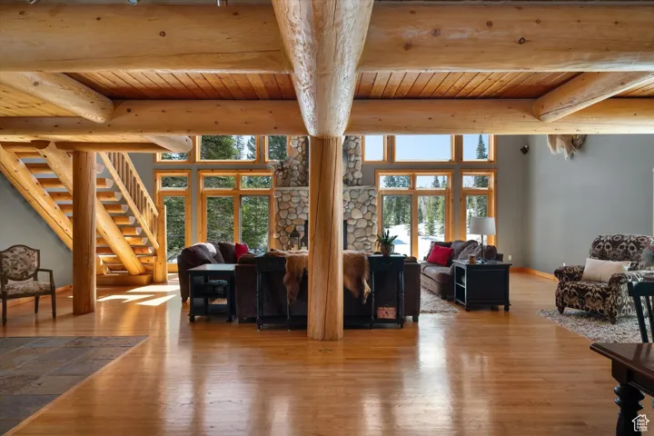 Living area with a wooden ceiling with exposed beams, hardwood / wood-style floors, healthy amount of natural light, and stairs