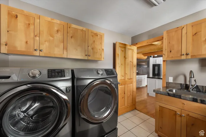 Laundry area featuring washer and dryer, cabinet space, and light tile patterned floors
