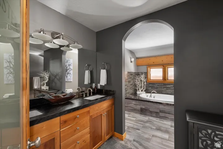 Bathroom featuring double vanity and a relaxing tiled tub