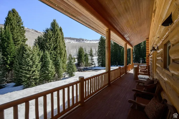 Snow covered deck with covered porch and a mountain view