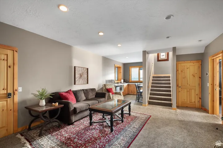Living room featuring stairway, light carpet, a textured ceiling, and recessed lighting