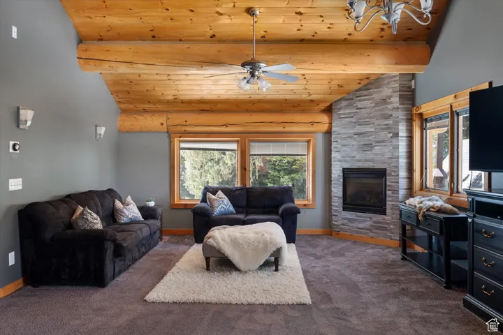 Living room featuring wooden ceiling, carpet floors, plenty of natural light, a ceiling fan, and a chandelier