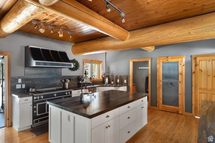 Kitchen featuring rail lighting, wooden counters, a wood ceiling with exposed beams, extractor fan, and double oven range