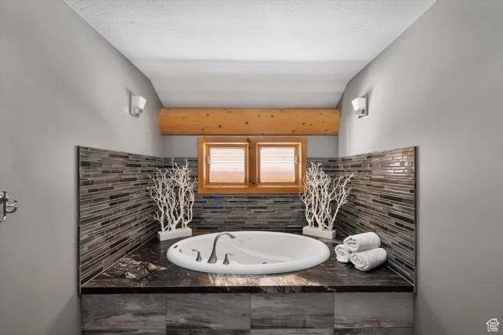 Bathroom featuring a tub with jets and tasteful backsplash