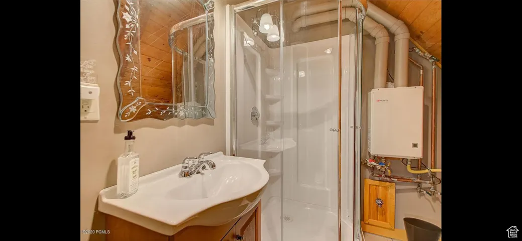 Full bath with a stall shower, tankless water heater, and vanity