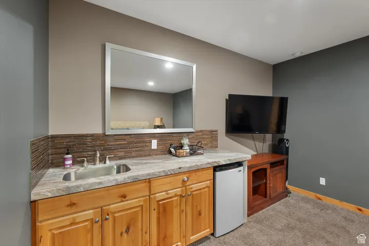Kitchen with light colored carpet, tasteful backsplash, light countertops, refrigerator, and recessed lighting