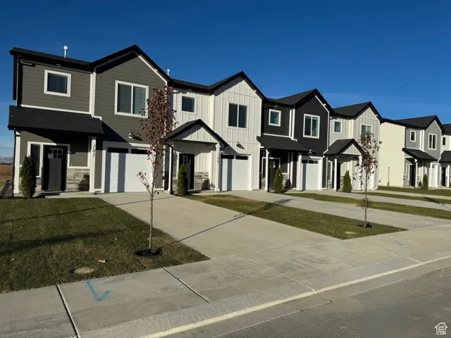 View of front of house with a garage, driveway, board and batten siding, and a residential view