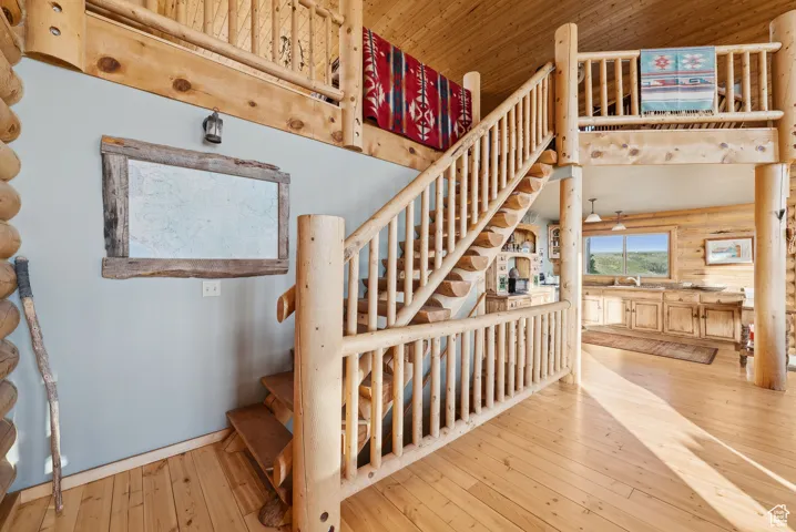 Staircase featuring hardwood / wood-style flooring, log walls, and wooden ceiling