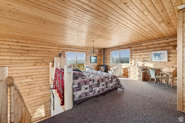 Carpeted bedroom with log walls, wooden ceiling, and a chandelier
