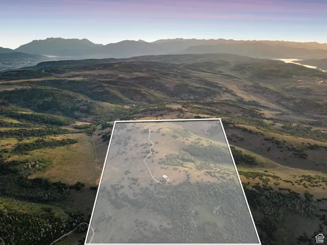 Aerial view of property and surrounding area with a mountain backdrop and property parcel outlined