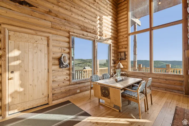 Dining area with rustic walls, a mountain view, wood-type flooring, and healthy amount of natural light