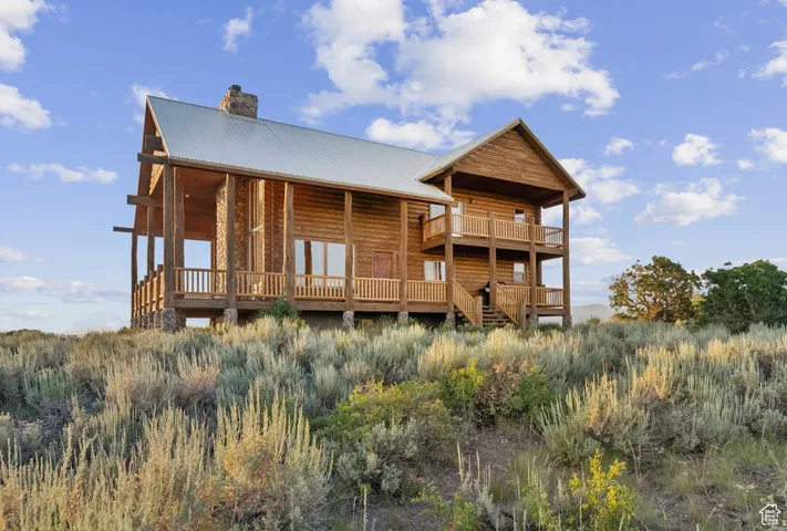 Rear view of property with a chimney, a metal roof, and a wooden deck