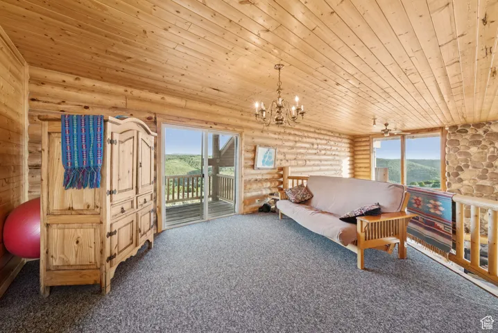 Carpeted living room featuring wood ceiling, rustic walls, a chandelier, plenty of natural light, and a mountain view