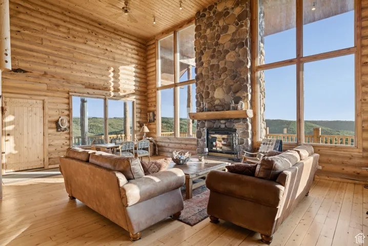 Living area featuring high vaulted ceiling, log walls, wood ceiling, a mountain view, and hardwood / wood-style flooring