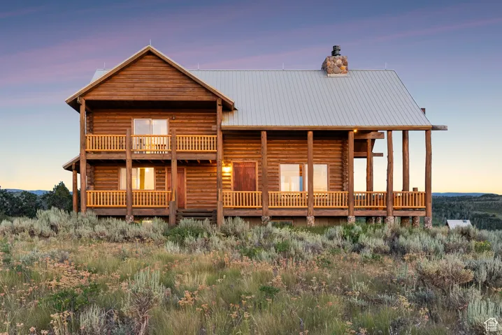 View of front of home featuring a chimney, log exterior, and a metal roof