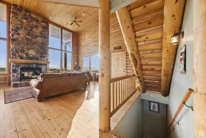 Living area featuring a high ceiling, hardwood / wood-style flooring, wood ceiling, log walls, and ceiling fan