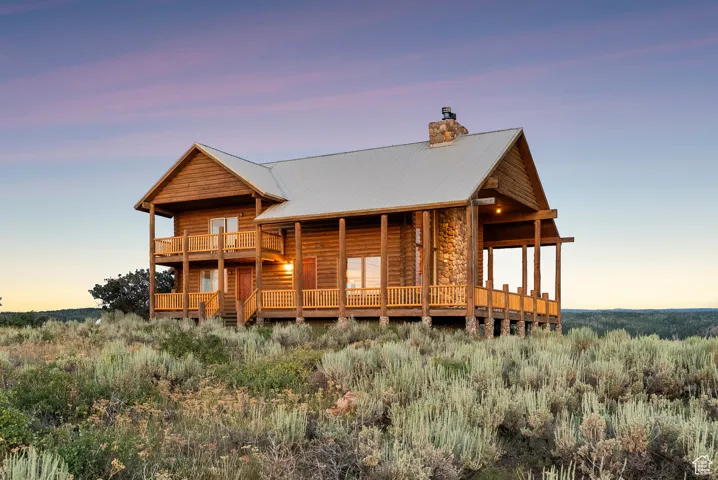 Log cabin featuring a metal roof, a chimney, and stone siding