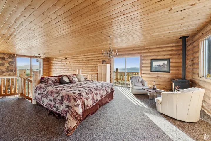 Bedroom featuring rustic walls, wooden ceiling, a wood stove, access to outside, and carpet
