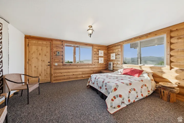 Bedroom featuring rustic walls and carpet