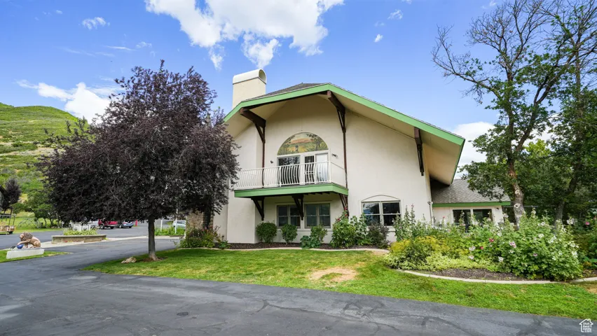 View of side of home with stucco siding, a chimney, and a yard