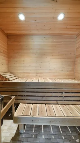 Relaxing sauna / steam room with wood ceiling and recessed lighting