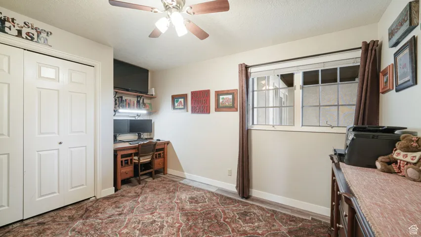 Office space with ceiling fan, a textured ceiling, and wood finished floors