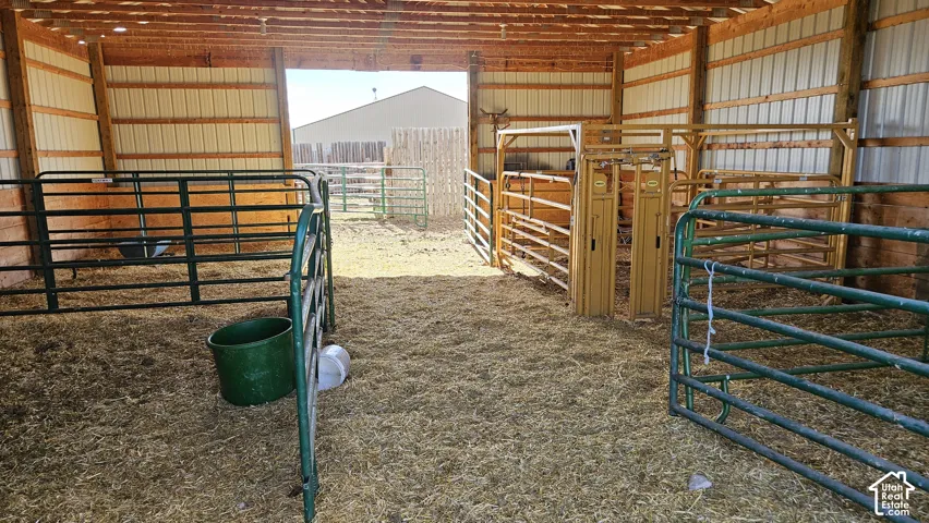 Barn interior featuring exposed wood beams, corrugated metal walls, and a dirt floor with straw