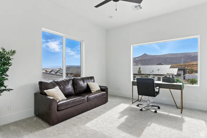 Office area with a ceiling fan, carpet, and a mountain view