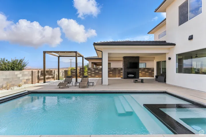 View of swimming pool with a patio area, an outdoor fireplace, and a pool with connected hot tub