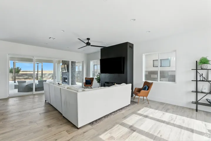 Living area with light wood-style floors, ceiling fan, and recessed lighting