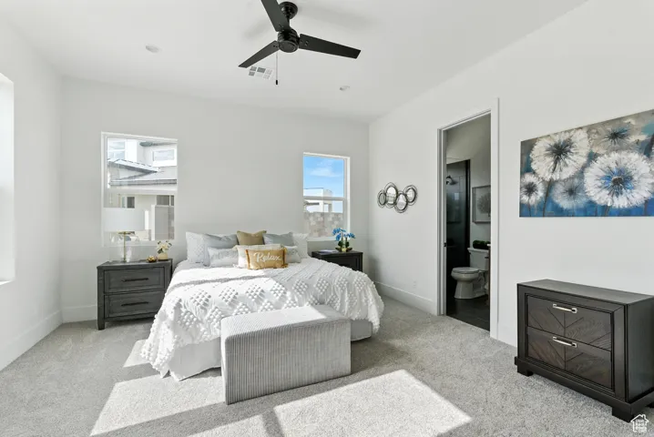 Bedroom featuring light carpet, ensuite bathroom, and ceiling fan