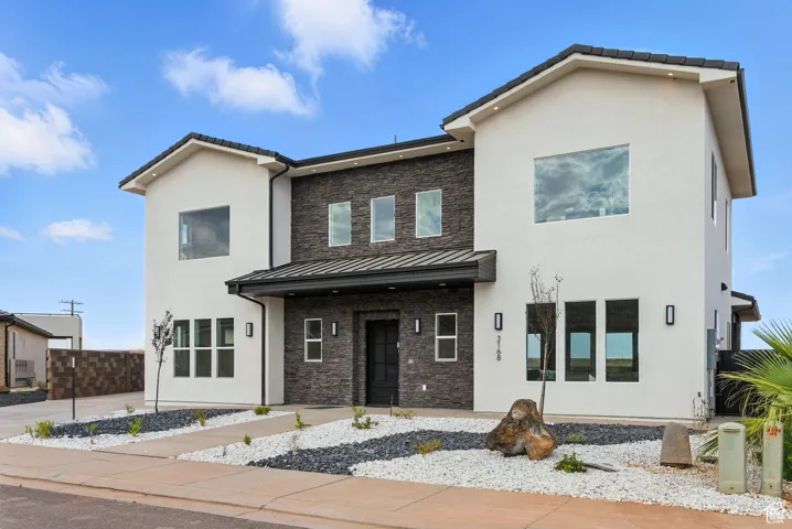 Contemporary home featuring a standing seam roof, stone siding, stucco siding, and a metal roof