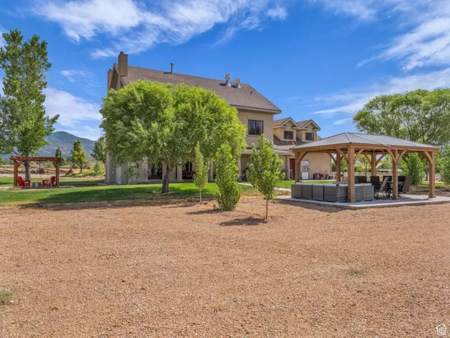 Rear view of house with outdoor lounge area, a gazebo, a chimney, and a mountain view