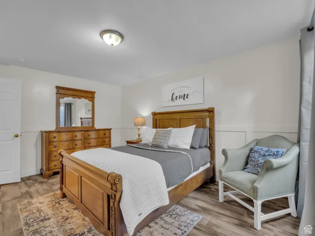Bedroom featuring light wood finished floors and a wainscoted wall