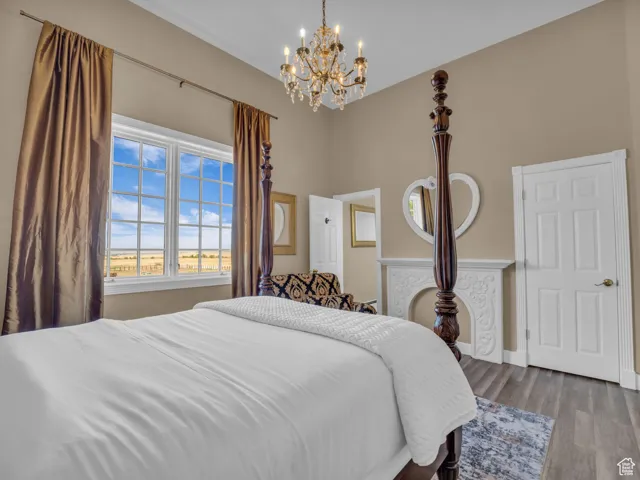 Bedroom featuring a chandelier, wood finished floors, and a high ceiling