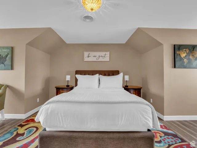 Bedroom with wood finished floors and lofted ceiling