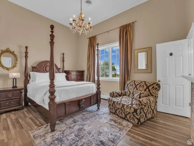 Bedroom featuring a chandelier, wood floors, and a baseboard heating unit