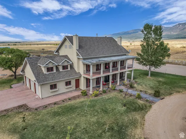 View of front of house with a chimney, a porch, a front yard, driveway, and a balcony