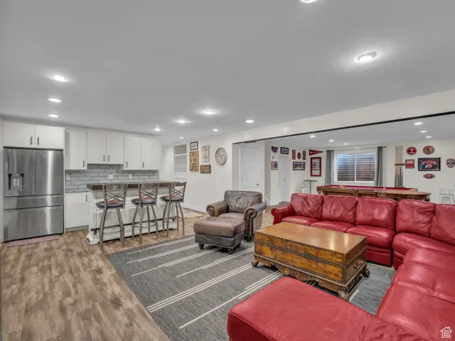 Living room featuring bar, light wood-type flooring, and recessed lighting